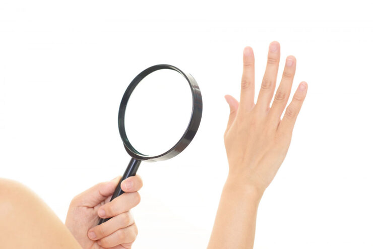 指先を虫眼鏡で見ている画像