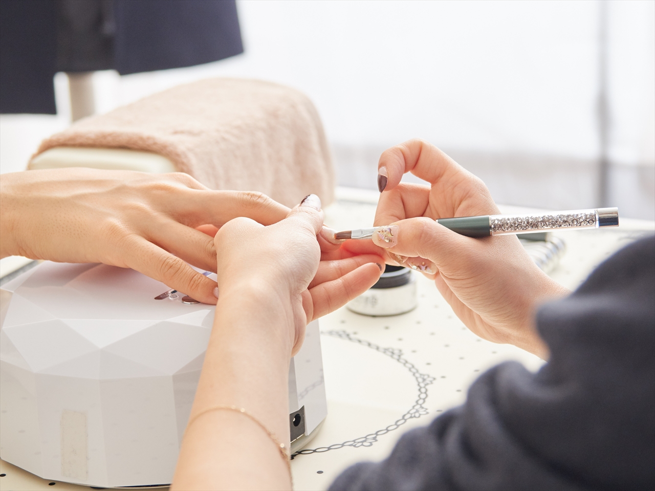 お客様の爪にネイルを塗るネイリストの手元