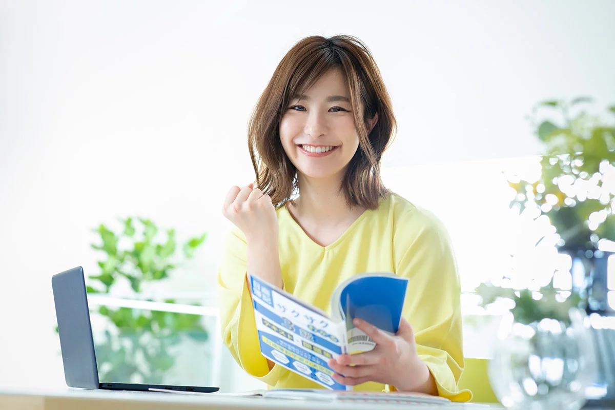 参考書を笑顔で開いている女性