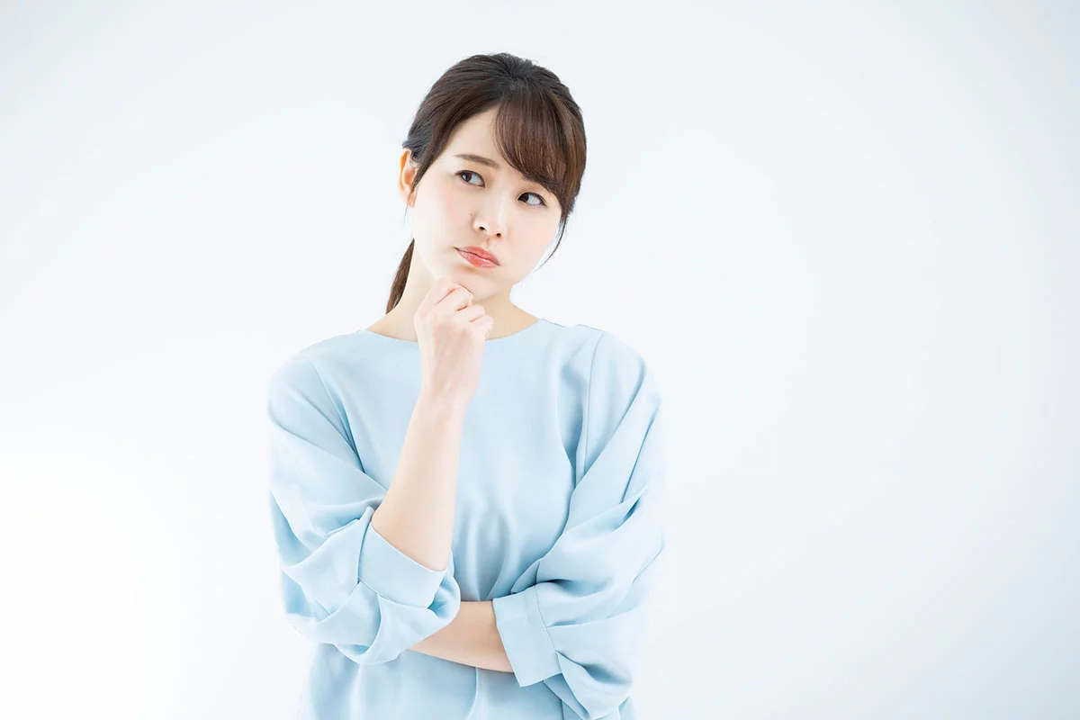 顎に指を当てて悩んでいる様子の女性