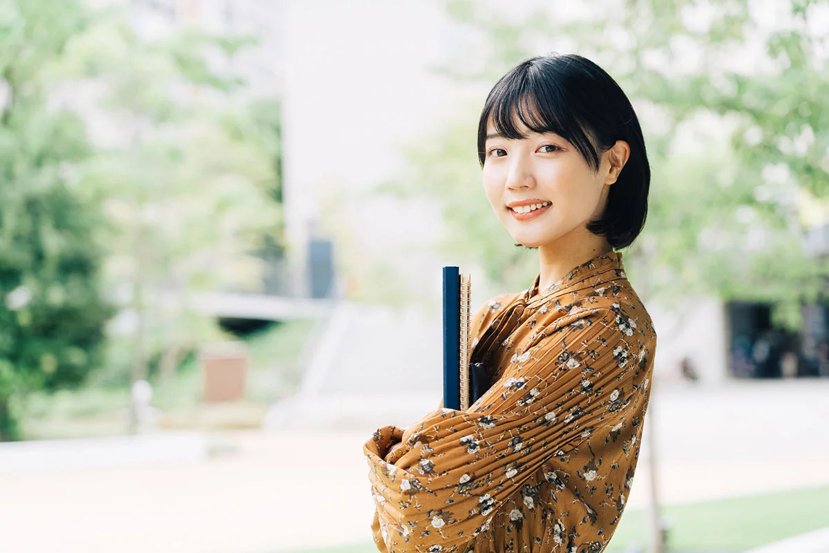 ノートを抱え微笑む女性
